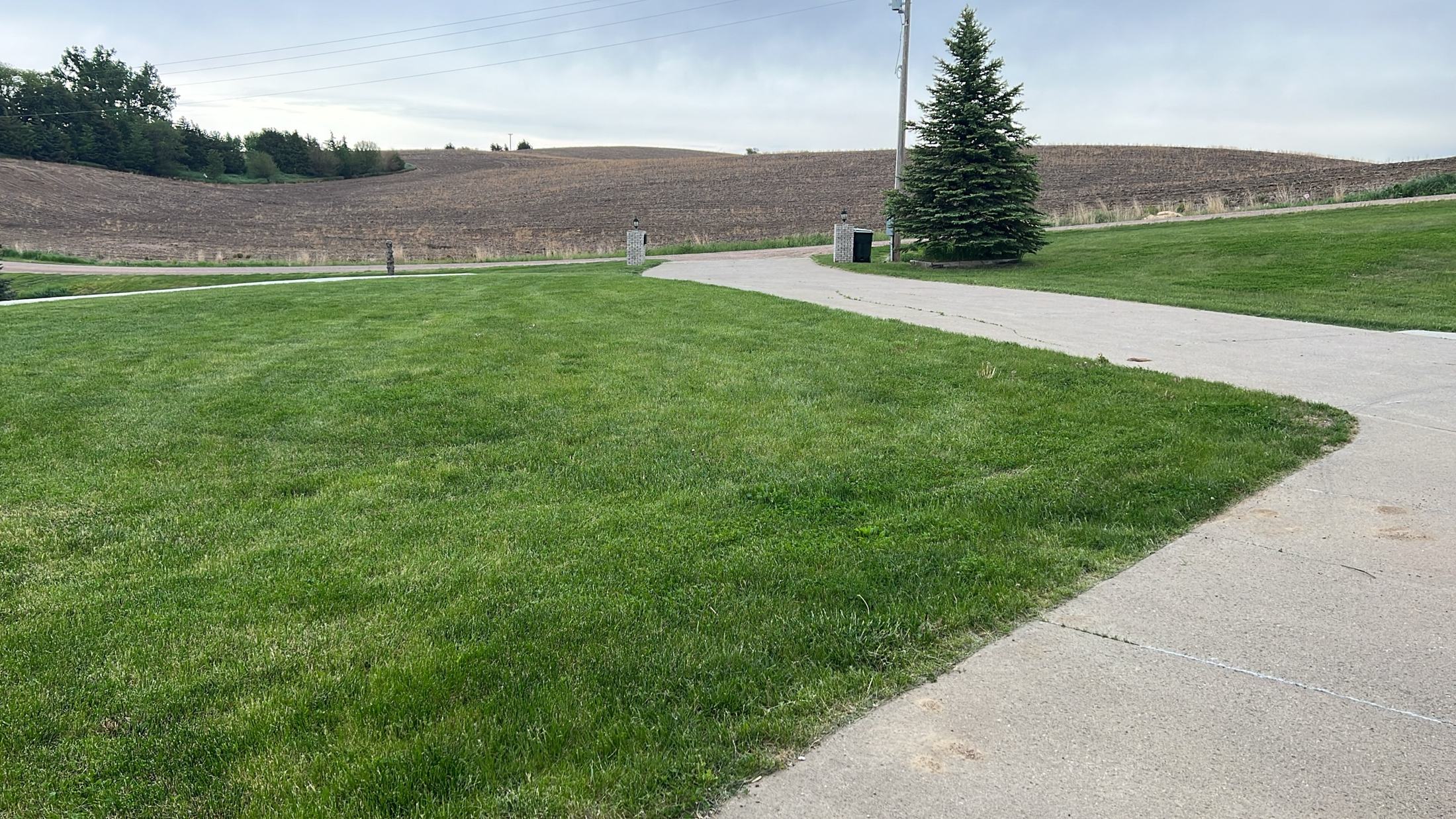 Driveway curving past the lawn toward rolling farm fields